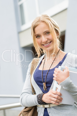 Young happy student holding books to school