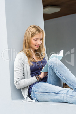 Student girl reading book outside of university