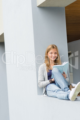 Young woman reading book outside of school