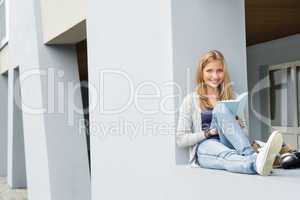 Teenage woman reading book outside of school