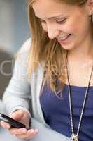 Smiling woman reading text message on cellphone
