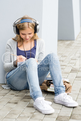 Student teenager writing and listening to music