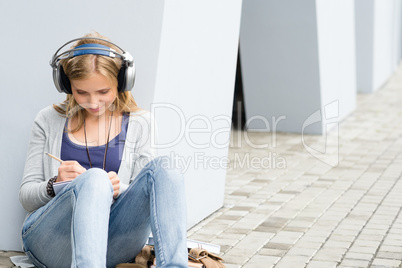 Student girl writing and listening to music