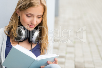 Student reading a book outside of university