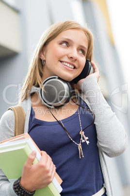 Young woman listening to music holding books