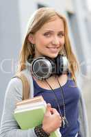 Teenage girl outdoor holding books with headphones