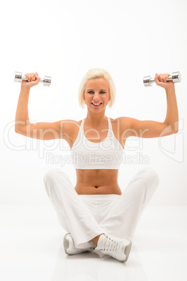 Fitness woman lifting dumbbells sitting white floor