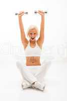Fitness woman lifting dumbbells sitting white floor
