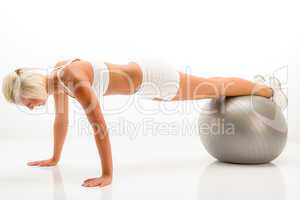 Woman gym ball pushups at white fitness