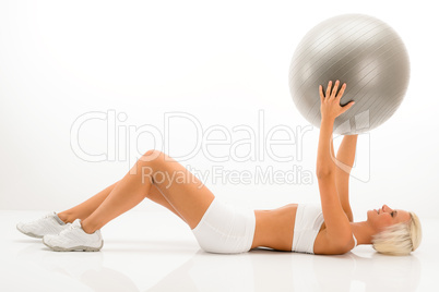 Slim blond woman exercises with fitness ball