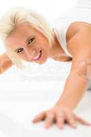 Woman doing push-ups exercises on white floor