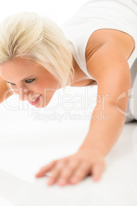 Woman doing push-ups exercises on white floor