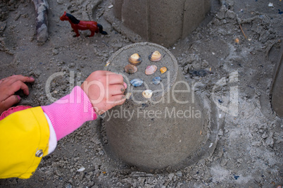 Kind beim Sandburg bauen