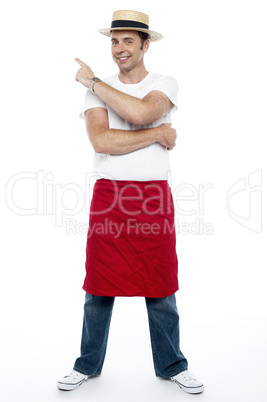 Man wearing a hat and apron pointing away