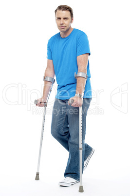 Painful expression by young man walking with help of crutches