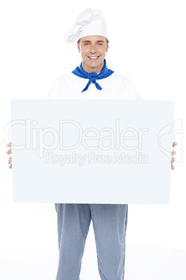 Handsome male chef holding ad board