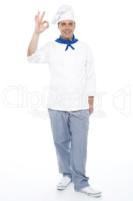 Full length portrait of chef showing okay sign