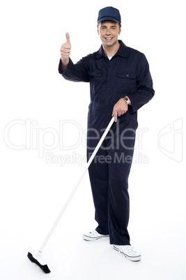 Cleaning guy holding broom and showing thumbs up