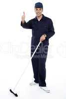 Cleaning guy holding broom and showing thumbs up