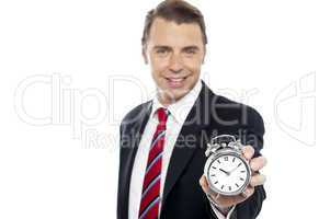 Smiling young consultant showing alarm clock