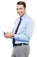 Smiling young manger sending sms from phone