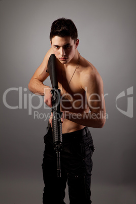 Handsome bare-chested soldier is holding a rifle