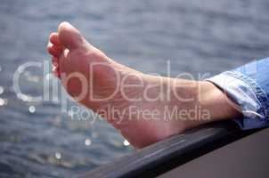 Fuß barfuß am Bootsrand über dem Wasser