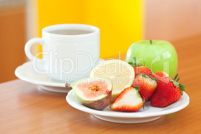 cup of tea,cookie,apple, lemon, fig and strawberries on a plate