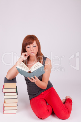 Eine junge Frau sitzt auf dem Boden neben einem Bücherstapel