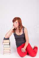 Eine junge Frau sitzt auf dem Boden neben einem Bücherstapel