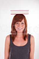 Eine junge Frau trägt ein Buch auf dem Kopf