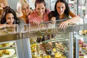 Women friends looking at cakes in cafe