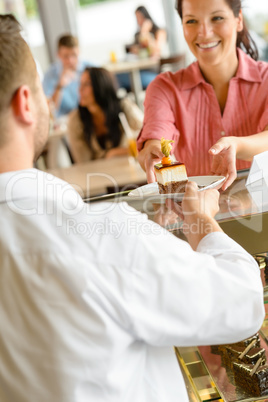 Waiter giving woman cake plate at cafe