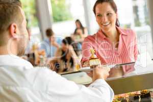 Waiter giving woman cake plate at cafe