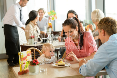 Couple feeding their child cake at cafe