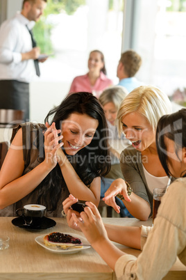 Friends looking at photographs and laughing cafe