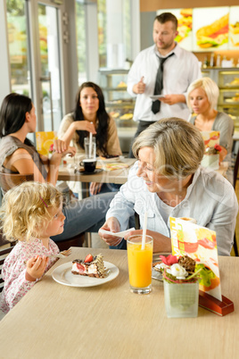 Child with grandmother at cafe eating cake