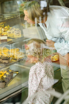 Grandchild and grandmother looking at cakes cafe