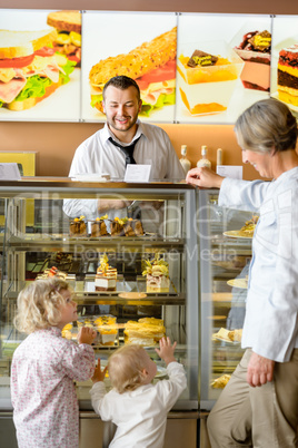 Grandchildren asking grandmother for cakes at cafe