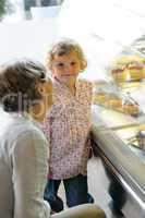 Woman with child girl choose cake bakery