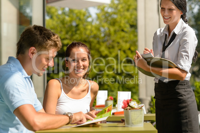 Couple at cafe ordering from menu waitress