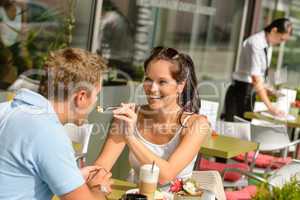 Woman feeding man cheesecake at cafe couple