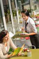 Waitress waiting for woman to order menu