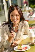 Woman eating cheesecake at cafe bar happy