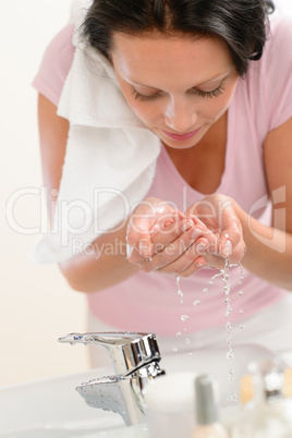 Woman washing face with water in bathroom