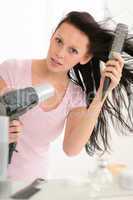 Woman blow-drying hair using round hairbrush