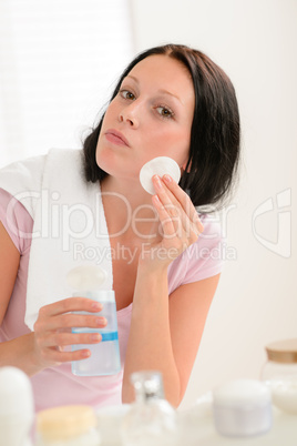 Woman cleaning face with cotton pad bathroom