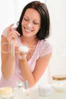 Smiling woman put moisturizer cream on nose
