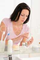 Young woman put moisturizer cream in bathroom