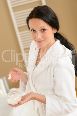 Woman with face moisturizer in bathroom